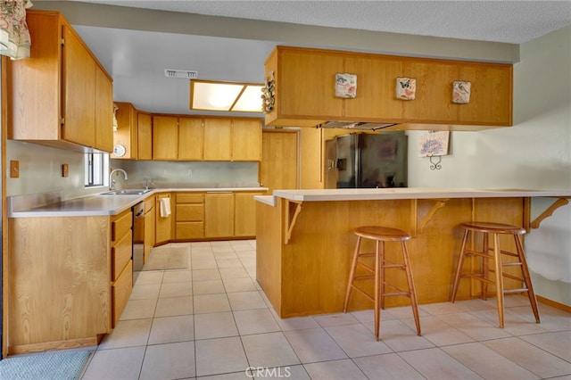 kitchen featuring a breakfast bar, a peninsula, fridge with ice dispenser, light countertops, and a sink