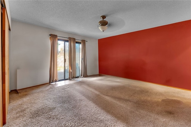 empty room featuring a textured ceiling and light colored carpet