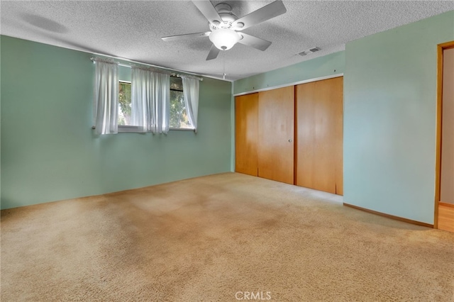 unfurnished bedroom with a closet, visible vents, light carpet, and a textured ceiling