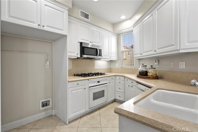 kitchen with a sink, visible vents, white cabinets, light countertops, and appliances with stainless steel finishes