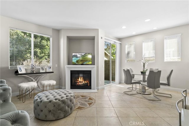 sitting room with recessed lighting, baseboards, a glass covered fireplace, and light tile patterned flooring