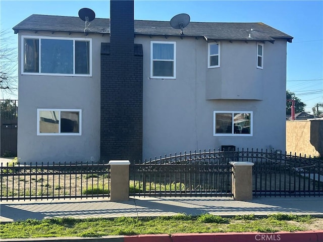 exterior space with brick siding, a fenced front yard, a gate, and stucco siding