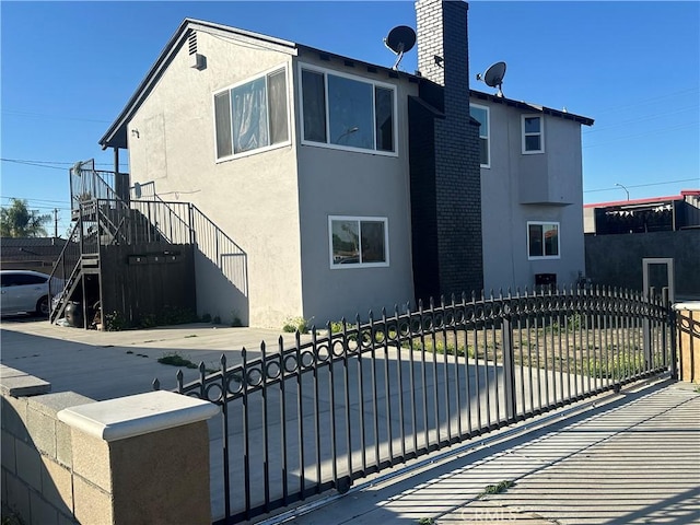 exterior space with a fenced front yard, a chimney, and stucco siding