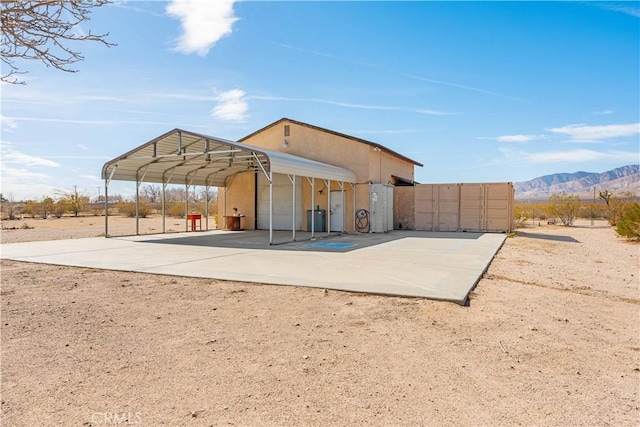 back of property with a garage, a mountain view, and stucco siding