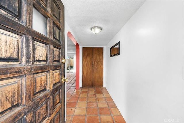 hall featuring light tile patterned flooring and a textured ceiling