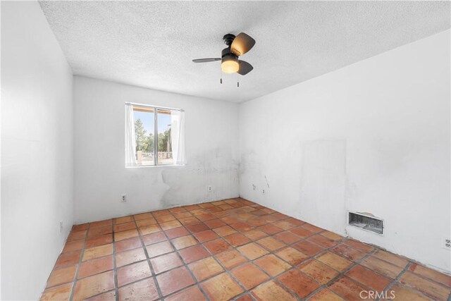 empty room featuring visible vents, ceiling fan, and a textured ceiling