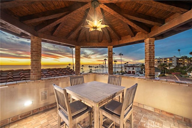 view of patio with a gazebo, outdoor dining space, and a water view