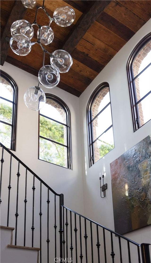 stairway featuring wood ceiling, beamed ceiling, and a high ceiling