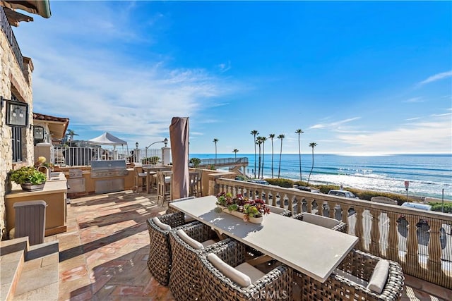 view of patio / terrace with a view of the beach, outdoor dining space, a water view, and area for grilling