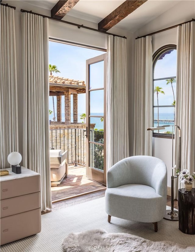 sitting room with a water view and lofted ceiling with beams