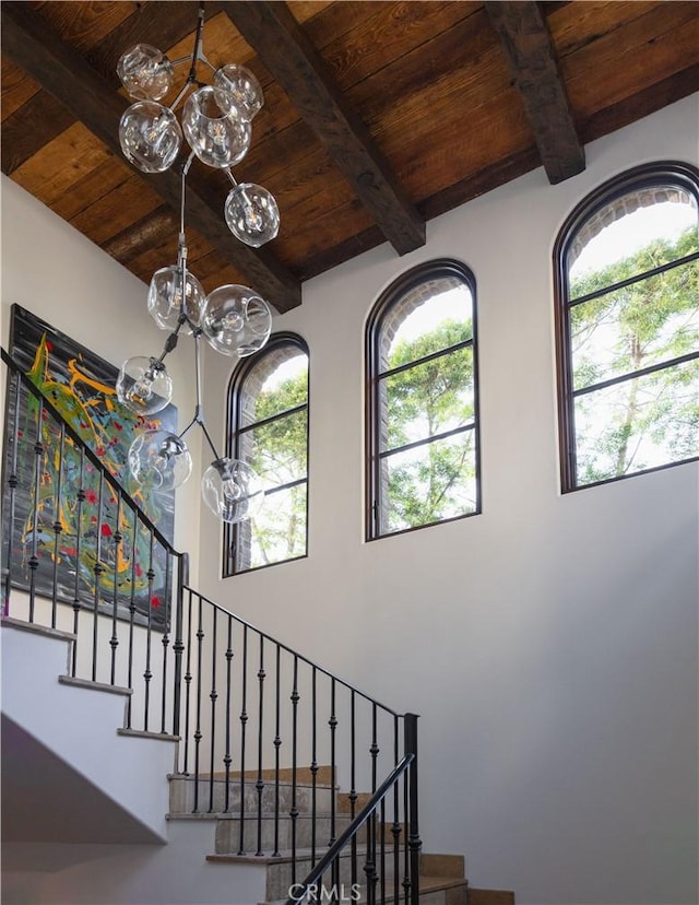 stairway featuring wooden ceiling, beamed ceiling, and a high ceiling