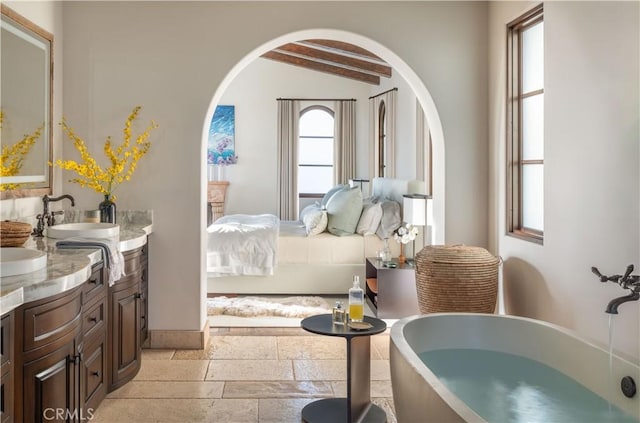 bedroom featuring a sink, lofted ceiling with beams, and stone tile flooring