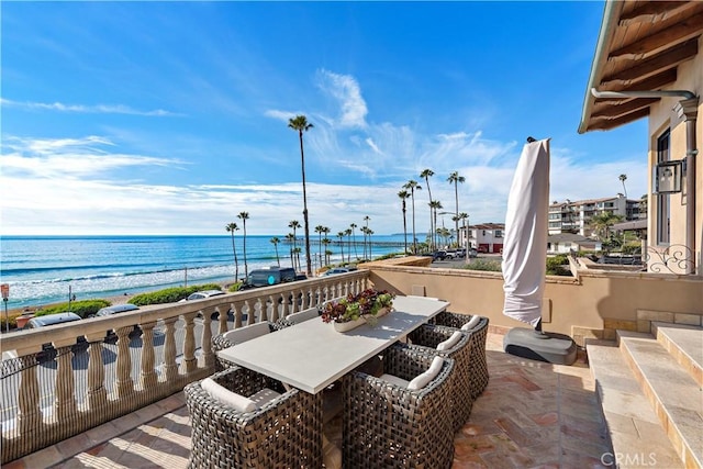 view of patio with a water view, a beach view, and outdoor dining area