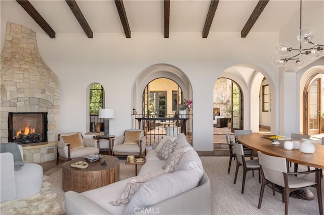 living room featuring arched walkways, an outdoor stone fireplace, and an inviting chandelier