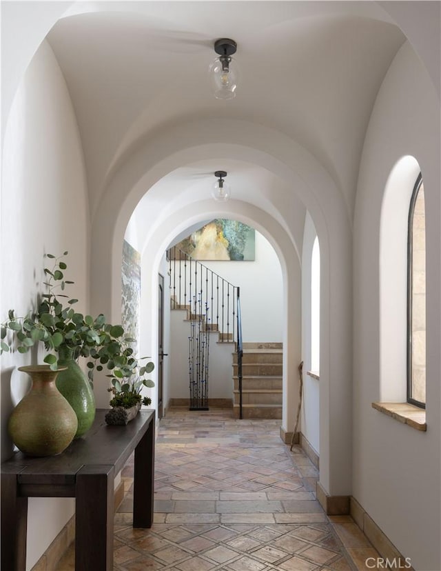 hallway featuring stairway, baseboards, and stone tile flooring