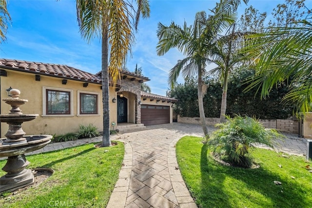 mediterranean / spanish-style home featuring an attached garage, driveway, a tiled roof, stucco siding, and a front lawn