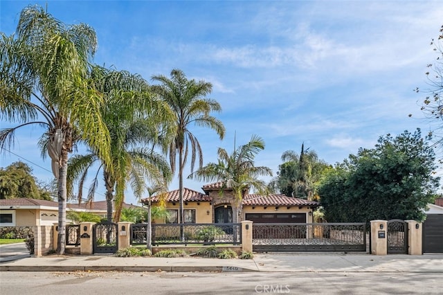 mediterranean / spanish-style home featuring a fenced front yard, a tile roof, and stucco siding