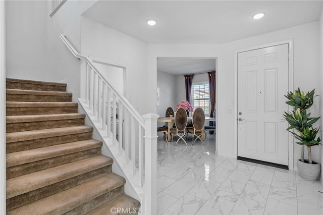 foyer featuring recessed lighting, marble finish floor, and stairway