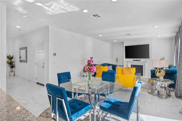 dining space with marble finish floor, a glass covered fireplace, visible vents, and recessed lighting