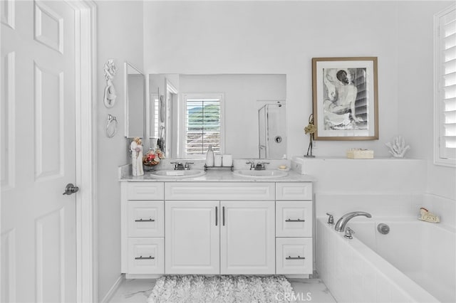 full bathroom featuring double vanity, marble finish floor, a garden tub, and a sink