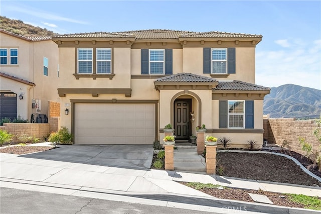 mediterranean / spanish-style house with stucco siding, concrete driveway, an attached garage, a mountain view, and a tiled roof