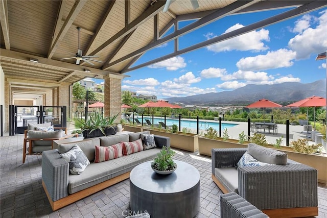 view of patio / terrace featuring outdoor lounge area, a ceiling fan, a mountain view, a pergola, and an outdoor pool