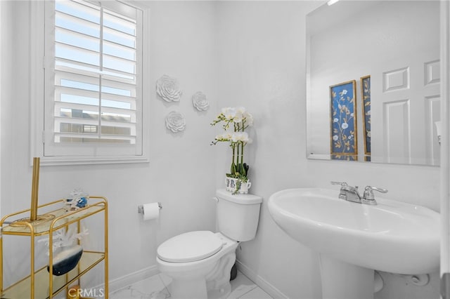 bathroom featuring marble finish floor, a sink, toilet, and baseboards