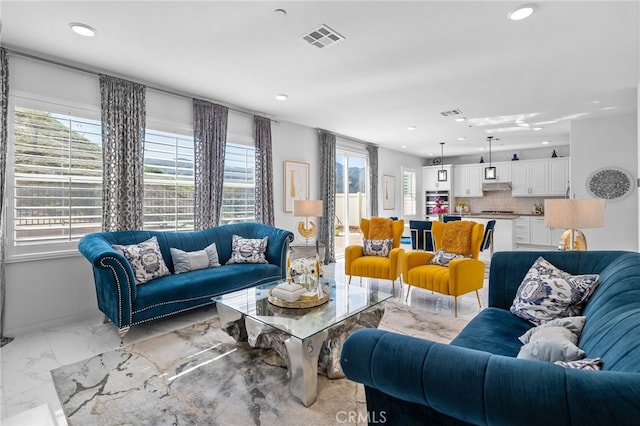 living area with recessed lighting, marble finish floor, visible vents, and baseboards