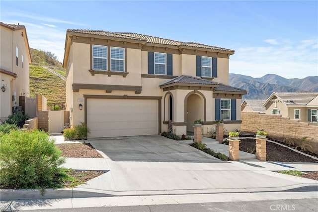 mediterranean / spanish-style home featuring a mountain view, a garage, fence, driveway, and stucco siding