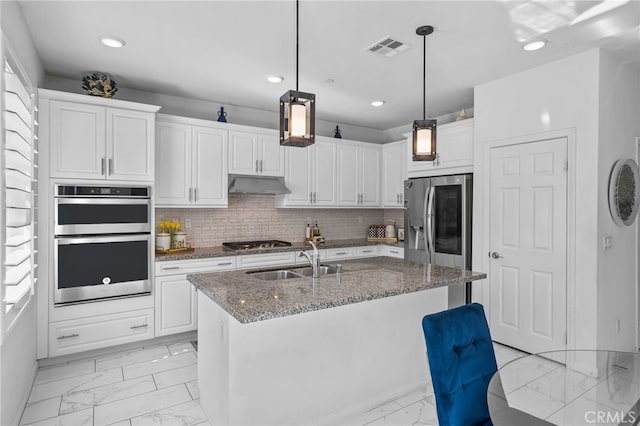 kitchen featuring under cabinet range hood, a sink, white cabinetry, marble finish floor, and appliances with stainless steel finishes