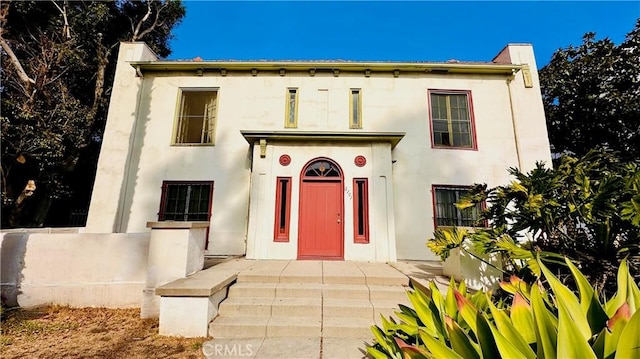 view of front facade with a chimney and stucco siding