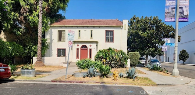 mediterranean / spanish home with a tiled roof, a chimney, and stucco siding