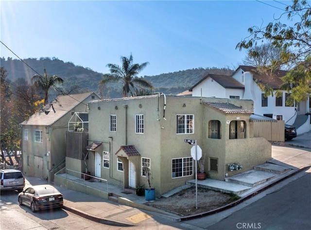 mediterranean / spanish-style home featuring a tiled roof, a mountain view, and stucco siding