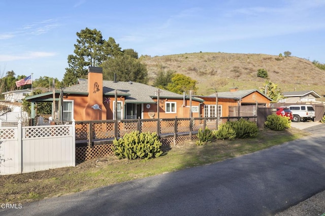 view of front of house with a chimney, fence, and a mountain view