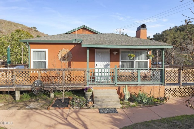 view of front of home featuring a shingled roof, a chimney, and stucco siding