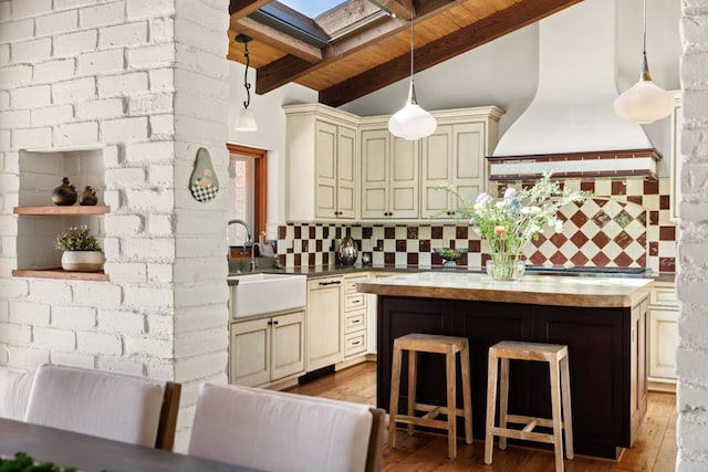 kitchen with dishwasher, decorative light fixtures, cream cabinets, premium range hood, and wooden counters