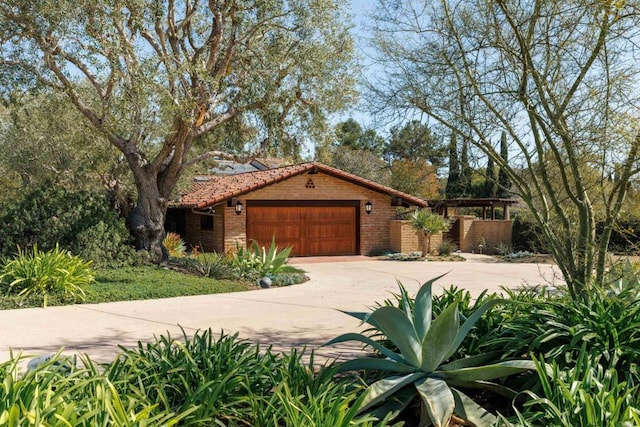 view of front of house featuring an attached garage, driveway, a tile roof, and brick siding