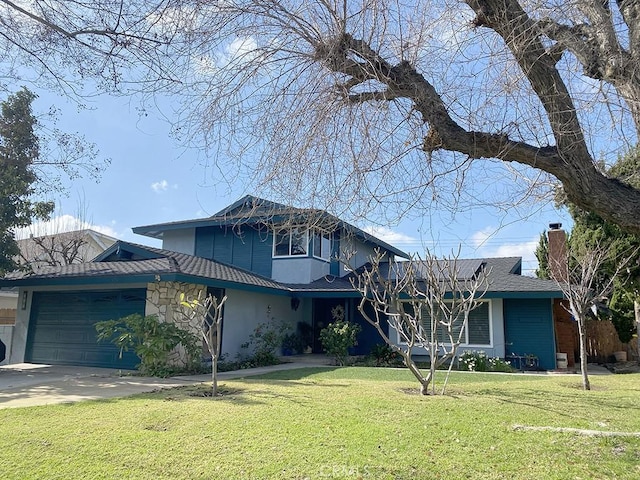 traditional-style home featuring an attached garage, driveway, a chimney, and a front yard