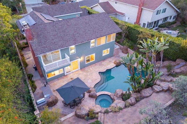 outdoor pool with an in ground hot tub and a patio area