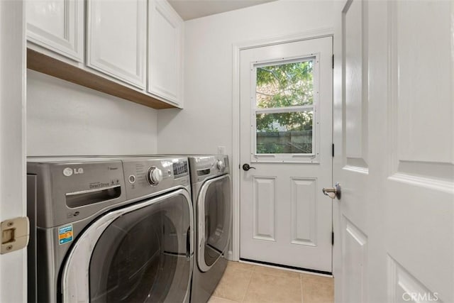 laundry room featuring washing machine and dryer, light tile patterned floors, and cabinet space