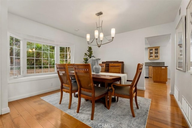 dining space featuring visible vents, light wood-style floors, baseboards, and a chandelier