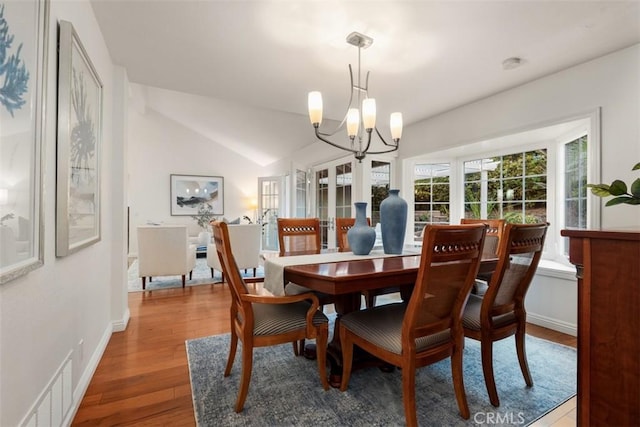 dining area featuring visible vents, lofted ceiling, wood finished floors, baseboards, and a chandelier