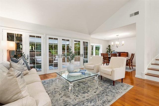 living room with visible vents, stairway, french doors, an inviting chandelier, and wood finished floors