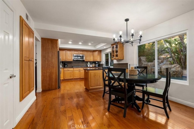 dining space featuring a notable chandelier, hardwood / wood-style flooring, a tray ceiling, recessed lighting, and baseboards