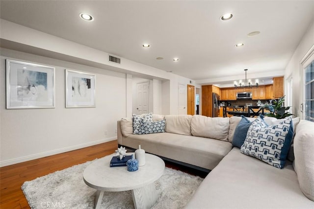 living room with wood finished floors, visible vents, baseboards, recessed lighting, and a notable chandelier