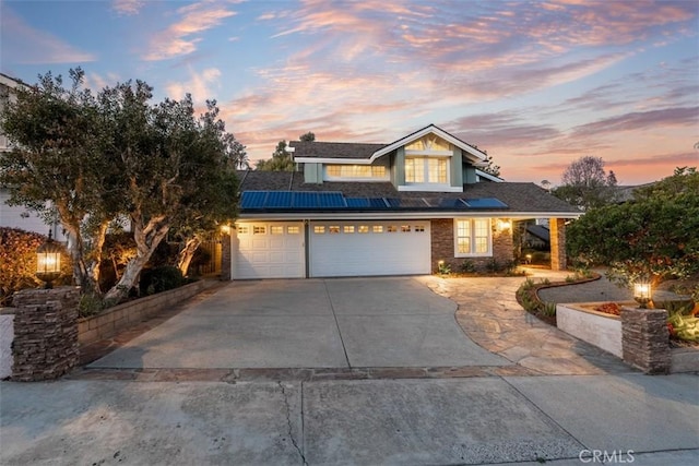 view of front of home featuring an attached garage, solar panels, and driveway