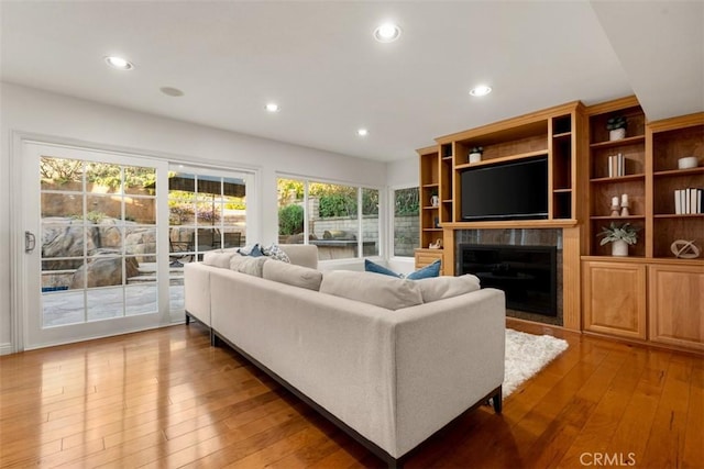 living room featuring recessed lighting, a fireplace, and light wood finished floors