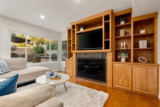 living room with a glass covered fireplace, recessed lighting, and light wood finished floors