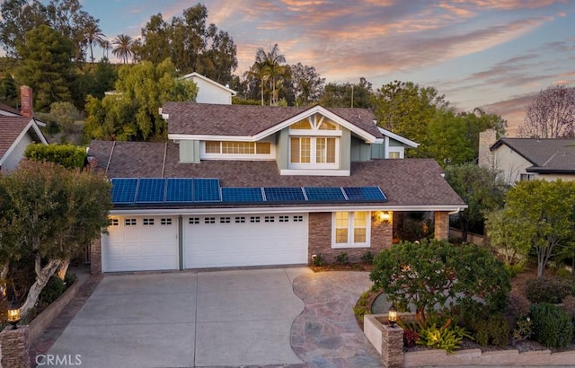 view of front of property with solar panels, driveway, and a garage