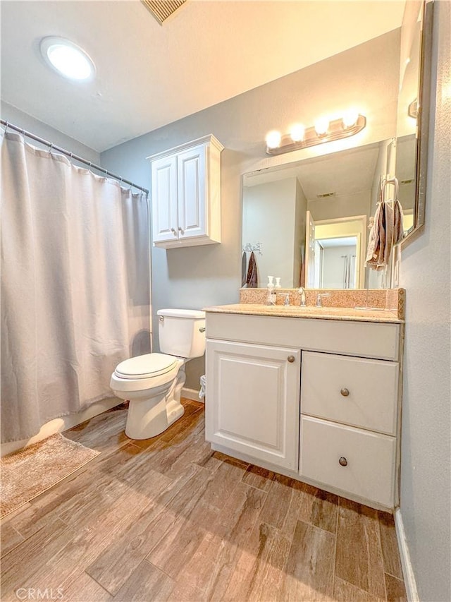 full bathroom with baseboards, vanity, toilet, and wood finished floors